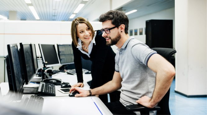 IT professional assisting a businesswoman at her office desk